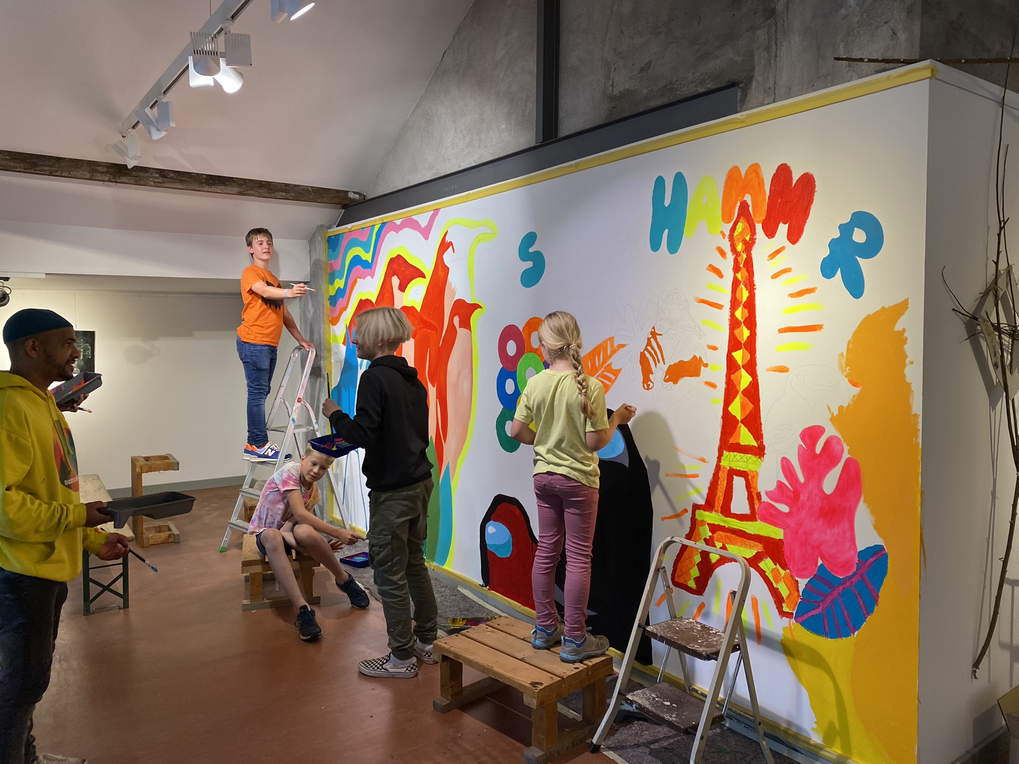 Eine Gruppe Kinder bemalt eine Wand